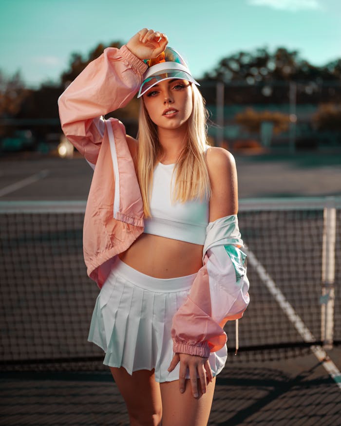Stylish woman posing on an outdoor tennis court in vibrant sporty attire.